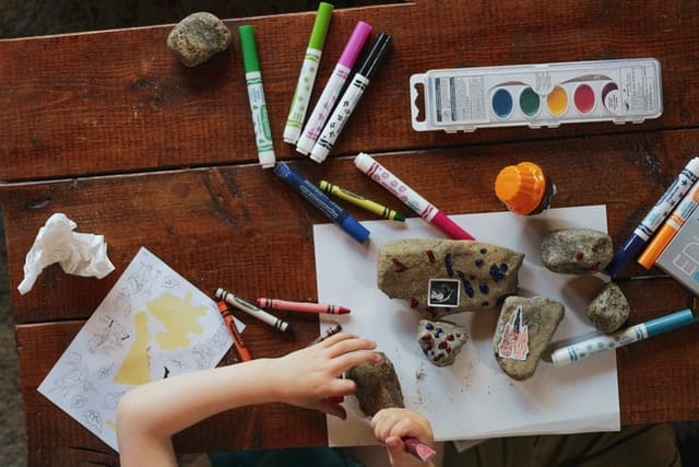 kid colouring rocks in the backyard