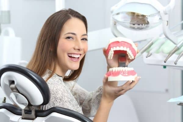 Smiling woman holding dentures