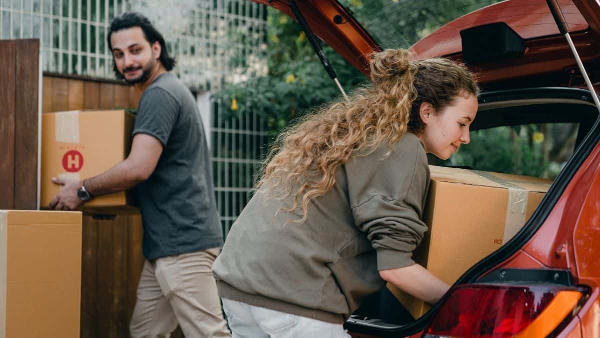 Moving house - husband and wife unpack boxes from car