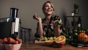 Smiling woman preparing to cold press some fruits and vegetables
