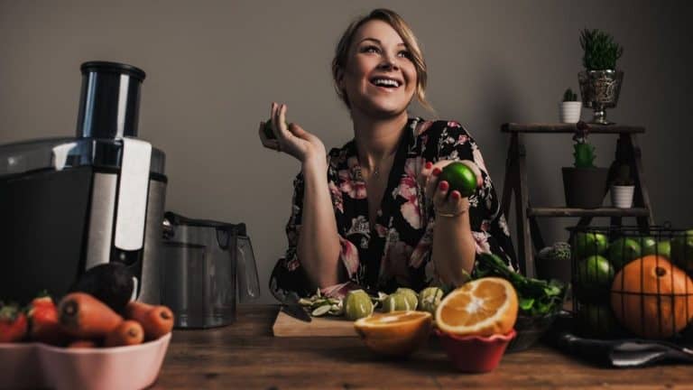 Smiling woman preparing to cold press some fruits and vegetables