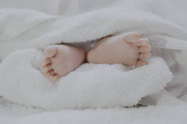 Tiny baby feet showing under white toweling