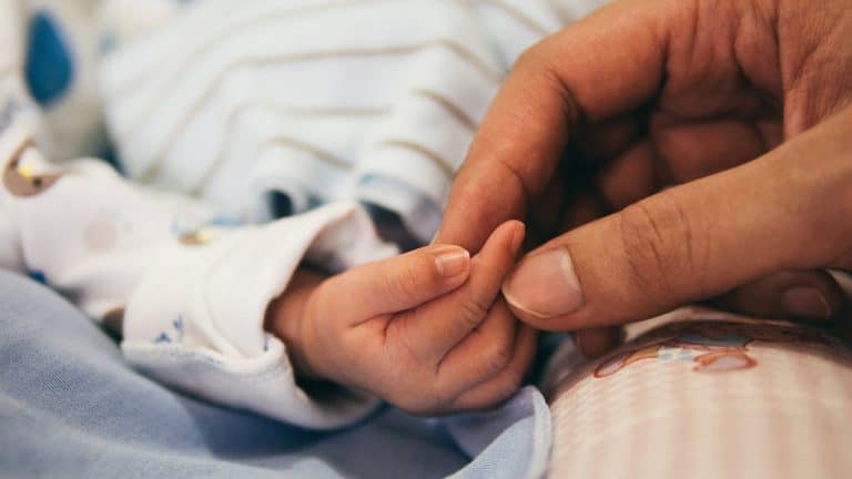 Tiny baby hand and mothers fingers closeup