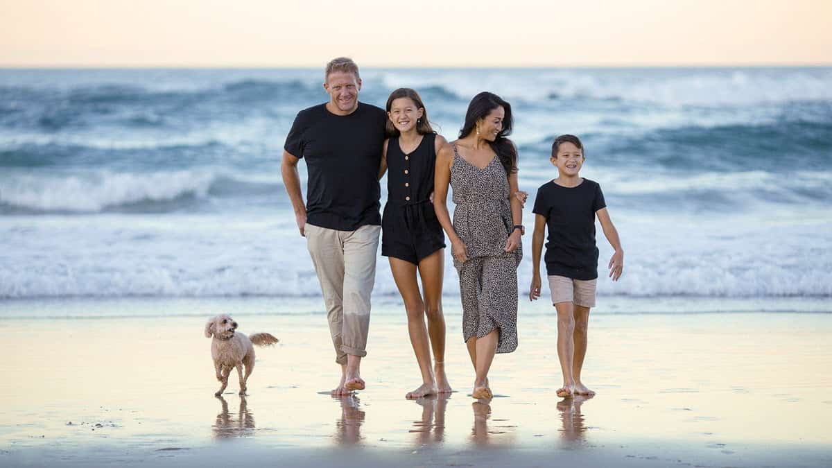 Happy family walking on the beach with their dog
