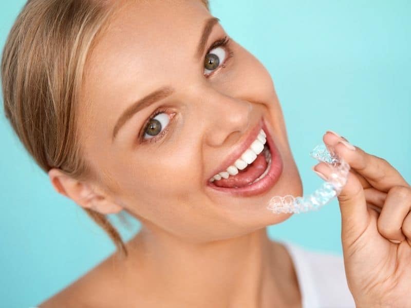 Woman smiling and holding teeth whitening tray