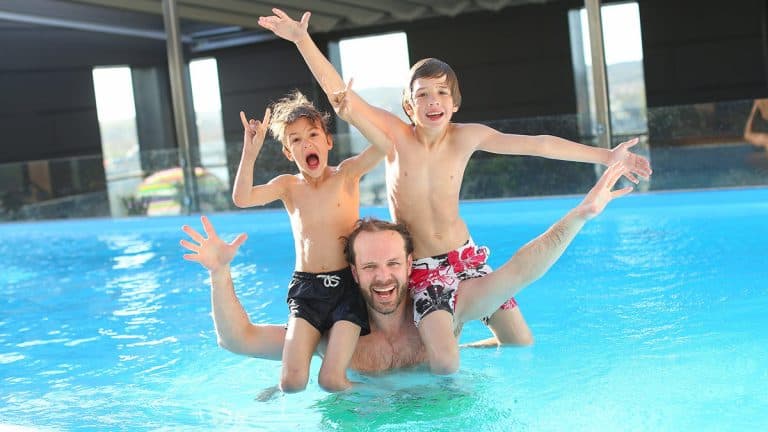 Father and two sons swimming in an immaculately clean swimming pool