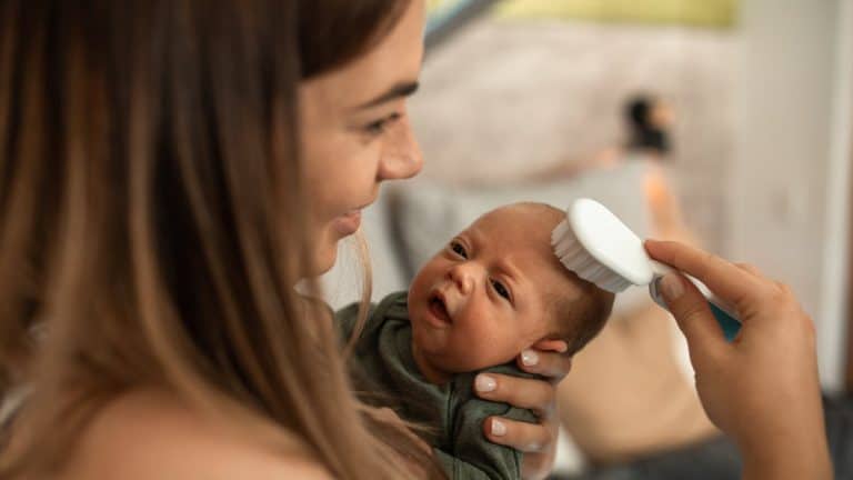 Mother gently brushing newborn baby head