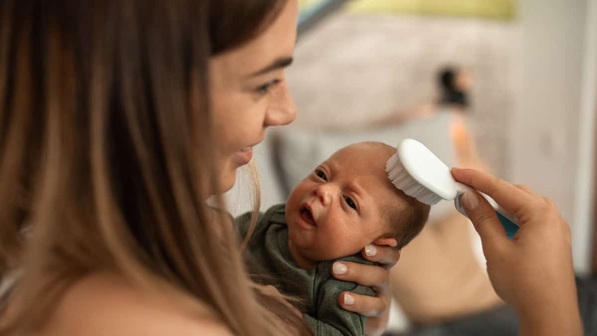 Mother gently brushing newborn baby head
