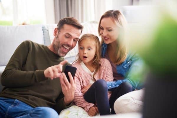 Daughter And Parents Looking At Mobile Phone