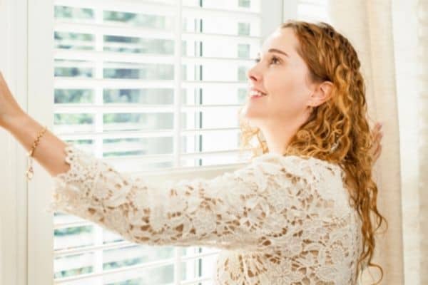 Person Standing Near Window With Blinds