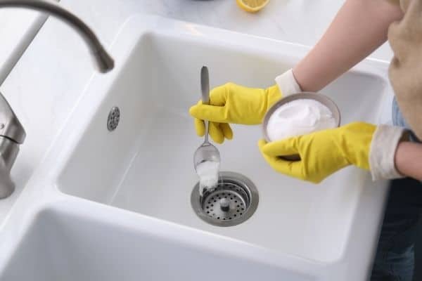 Woman Using Baking Soda To Clean Sink