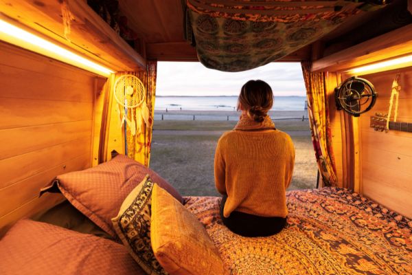 Woman Sitting On Bohemian Campervan Near The Sea